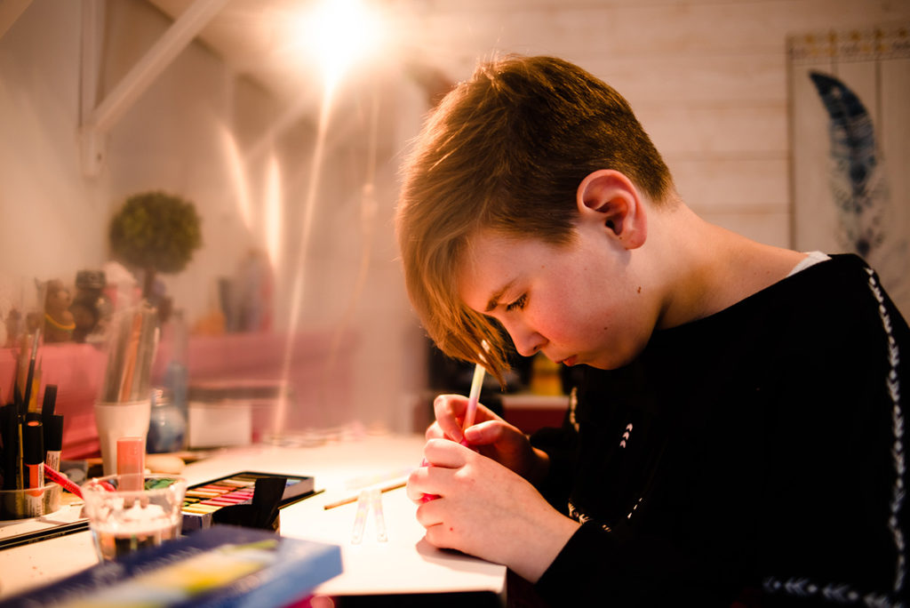 Comment rester créatif en photographie de portrait ? Portrait d'une jeune fille qui réalise une activité manuelle.