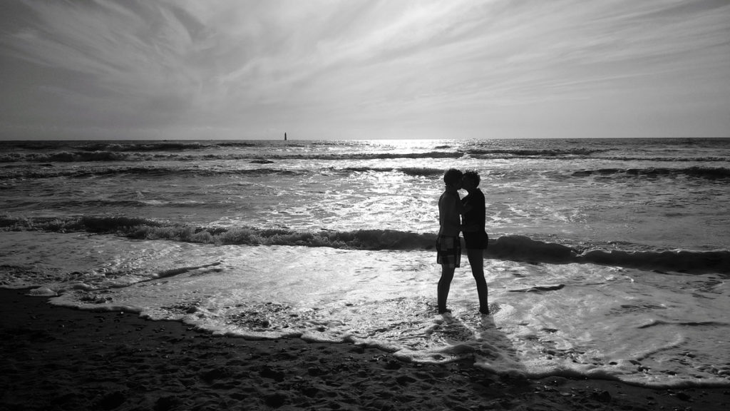 Mon projet photo 52 : qu’est-il devenu ? Photographie en noir et blanc d'un jeune couple sur la plage. Silhouettes en contre-jour.