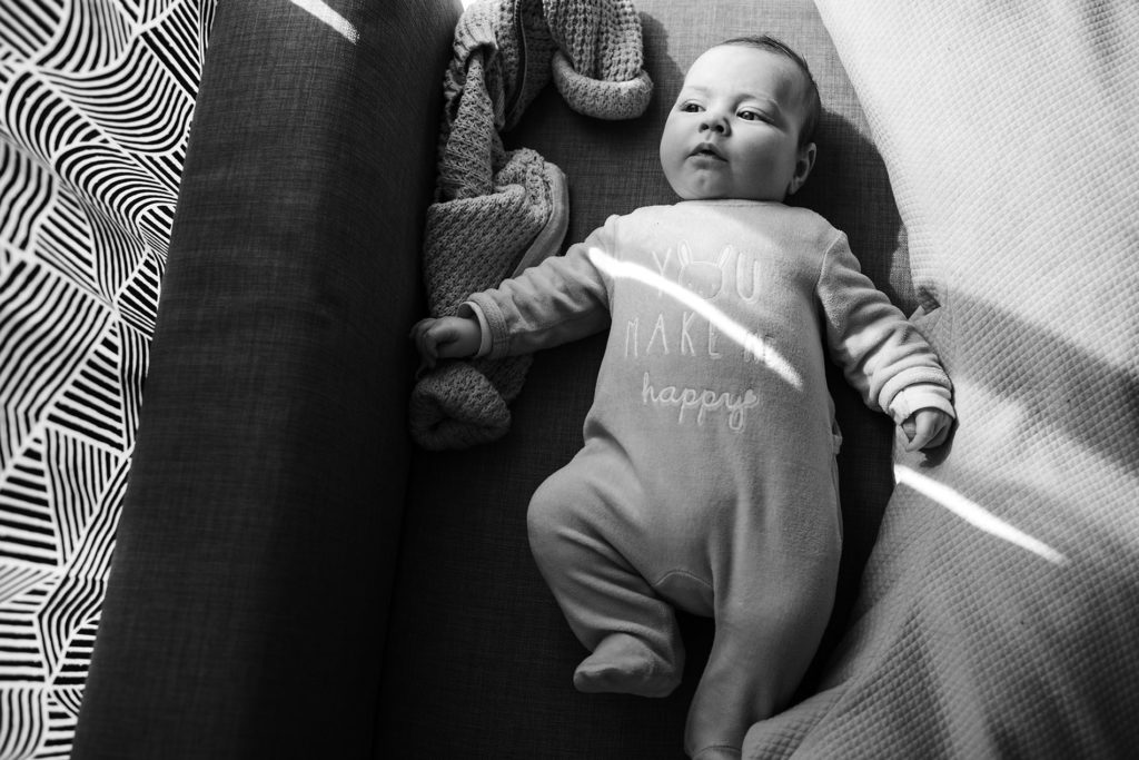 Reportage du quotidien près de Rennes. Photographie en noir et blanc d'un bébé allongé sur un canapé.