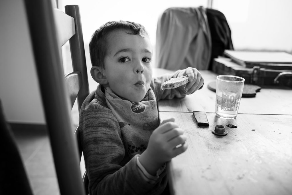 Reportage du quotidien près de Rennes. Photographie en noir et blanc d'un petit garçon prenant son gouter.