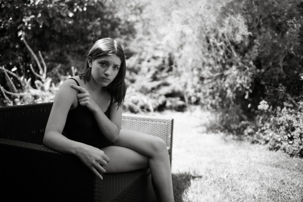 Pourquoi je fais le choix de la photographie en noir et blanc ? Portrait en faible profondeur de champ et en noir et blanc d'une jeune fille dans son jardin. Reportage de famille.